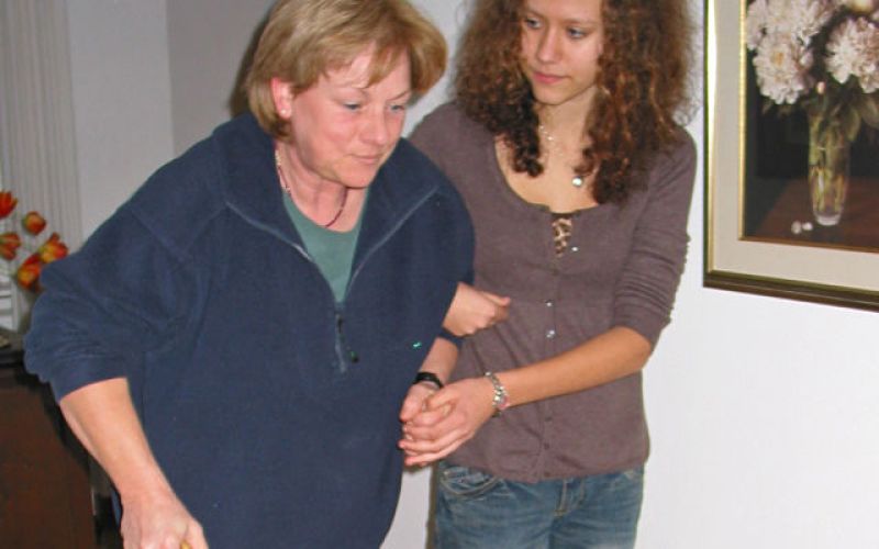 caregiver helping woman walk