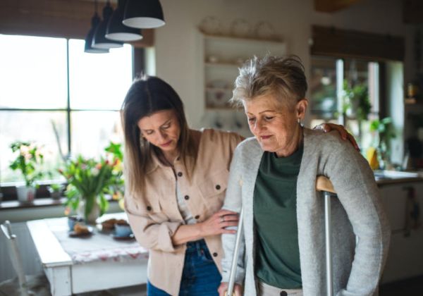 Caregiver helping woman to kitchen